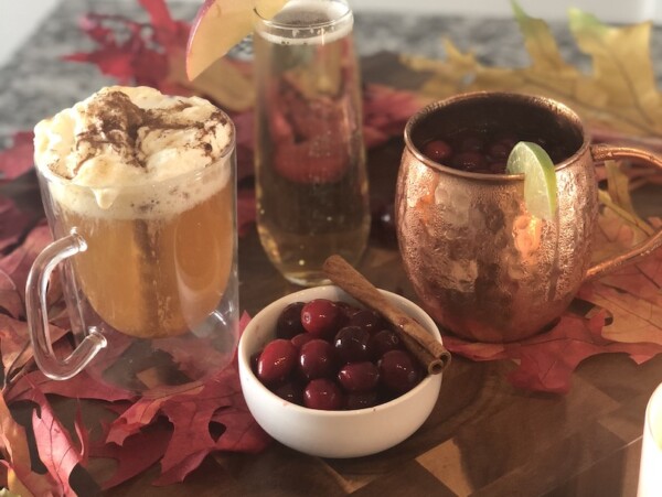 photo of three different fall cocktails on a wooden surface