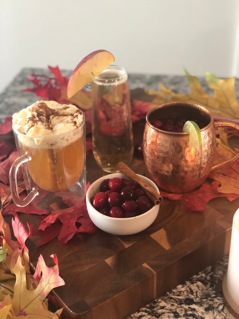 photo of three different fall cocktails on a wooden surface