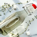 Photo of thyme simple syrup in a glass jar surrounded by thyme sprigs