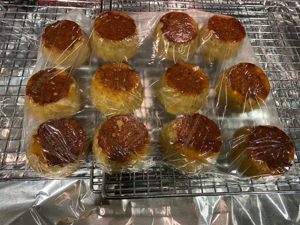 Photo of muffins wrapped in plastic wrap on a cooling rack to lock in moisture