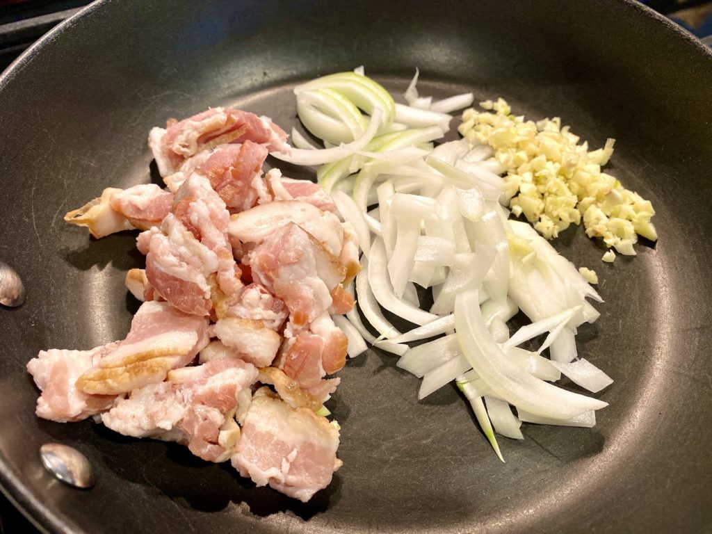 photo of chopped bacon, onions, and minced garlic in a nonstick pan