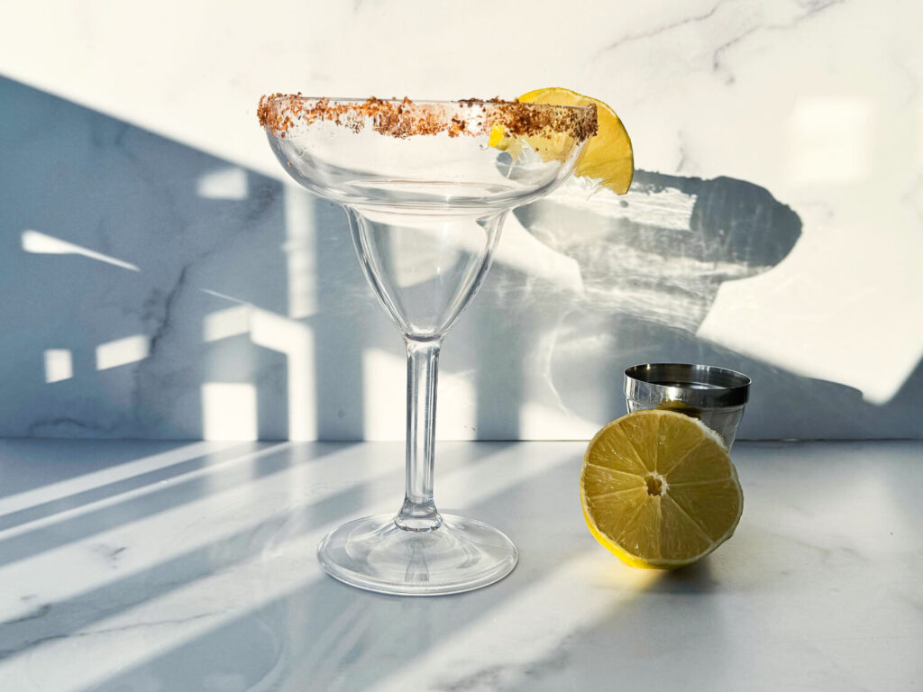 Photo of a margarita glass rimmed with Tajín and a lime slice