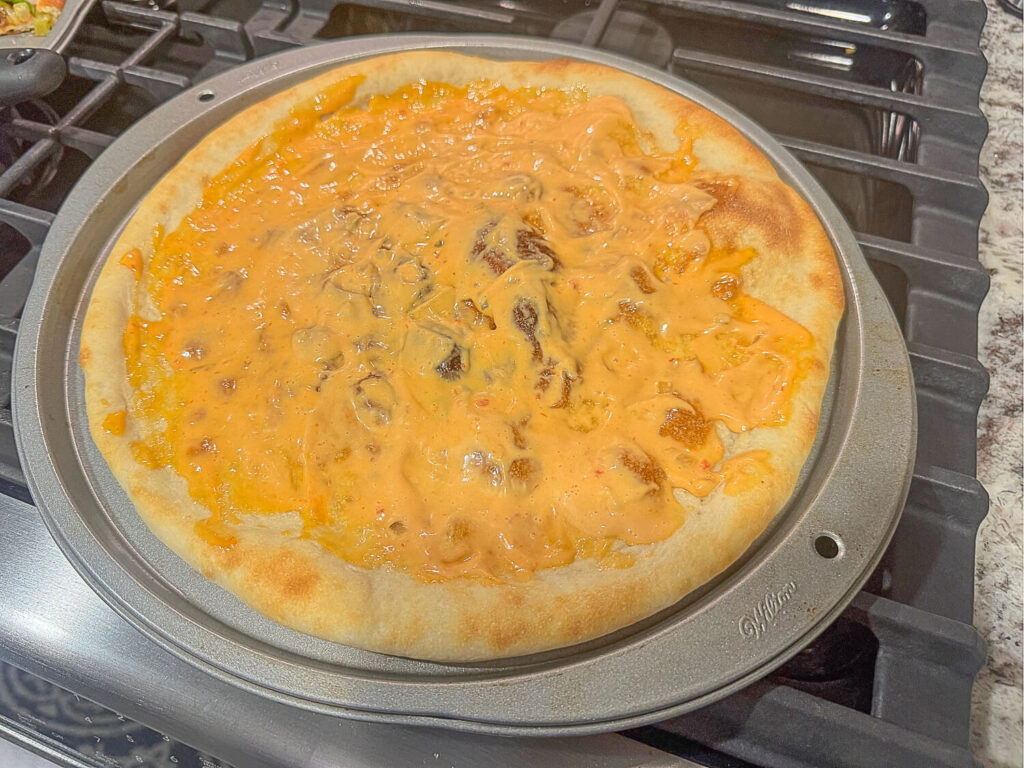 photo of a thin layer of thousand island dressing on pizza crust 