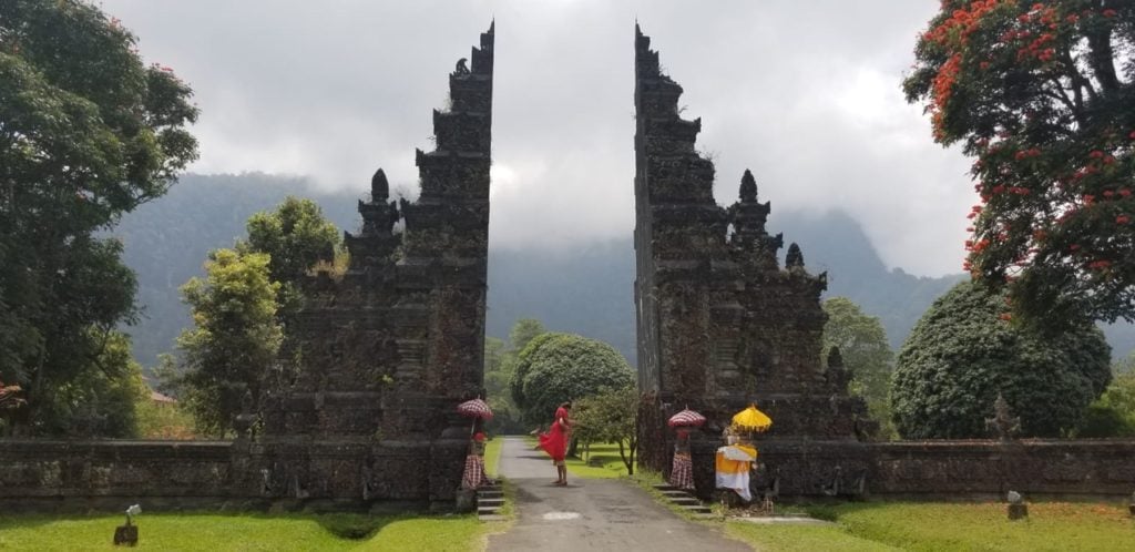 a photo of elicit folio in a red dress in front of the famous gates in Bali at the Handara Golf Resort