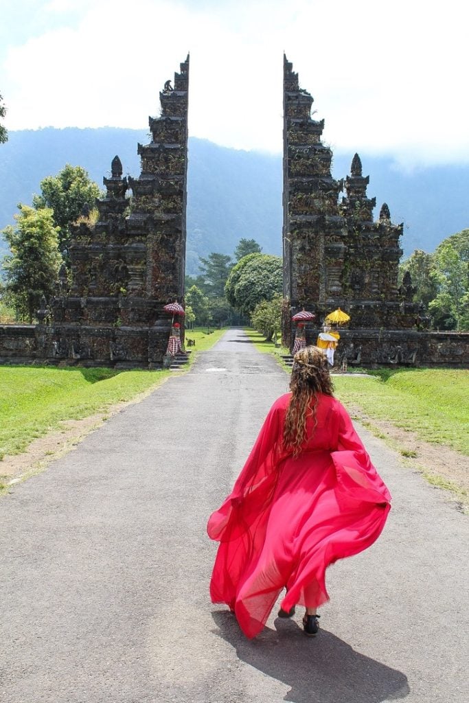a photo of elicit folio in a red dress in front of the famous gates in Bali at the Handara Golf Resort