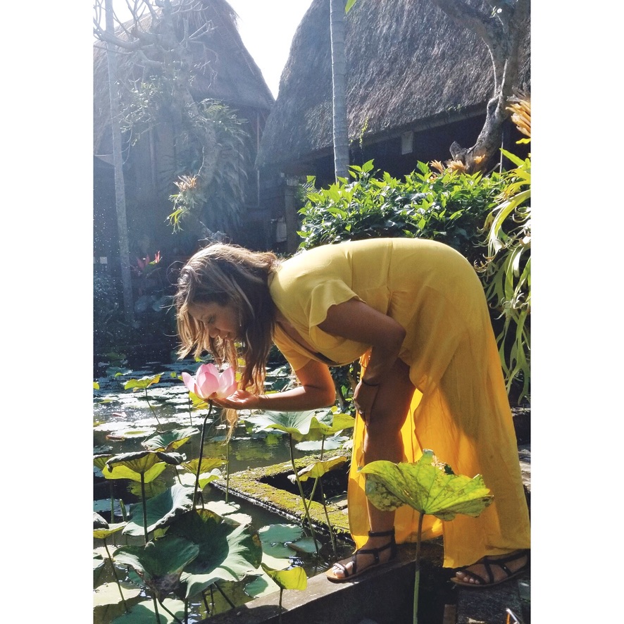 Photo of Elicit Folio in a yellow dressing smelling a flower outside the restaurant of Bebek Bengil