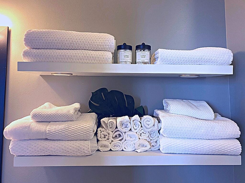Photo of white towels on floating shelf in bathroom