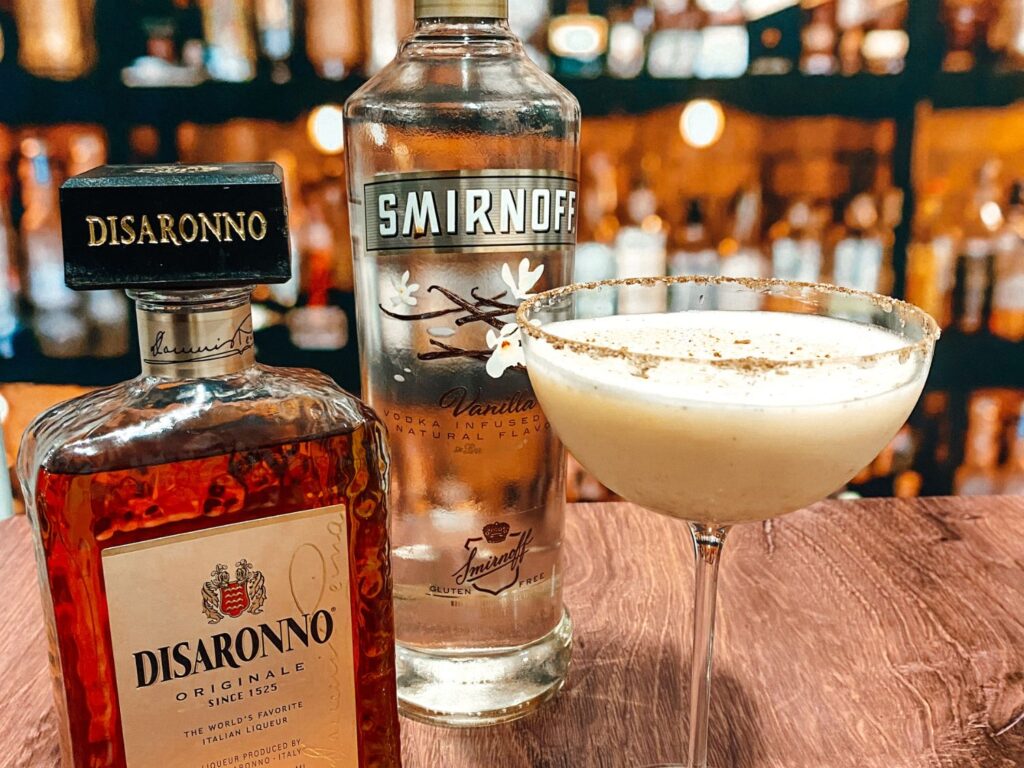 Photo of Vanilla Vodka and Disaronno Liqueur next to a glass of spiked eggnog