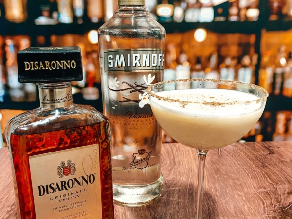 Photo of Vanilla Vodka and Disaronno Liqueur next to a glass of spiked eggnog