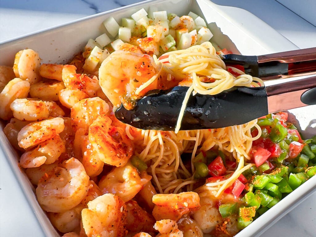 shrimp pasta salad in some black tongs