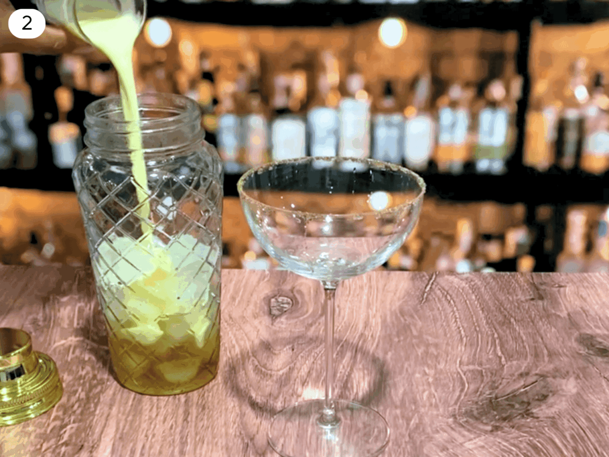 step 2 photo showing eggnog being poured into the shaker with alcohol