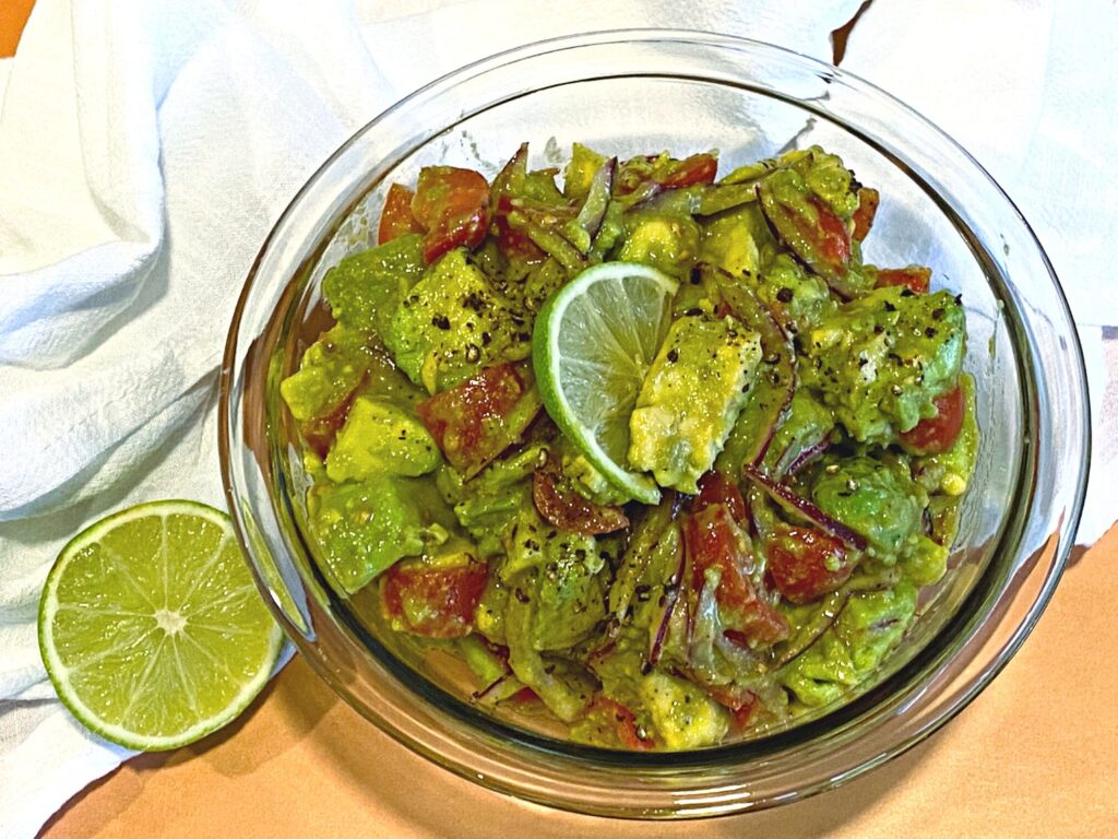 Close up of avocados, red onions and cherry tomatoes in mixing bowl