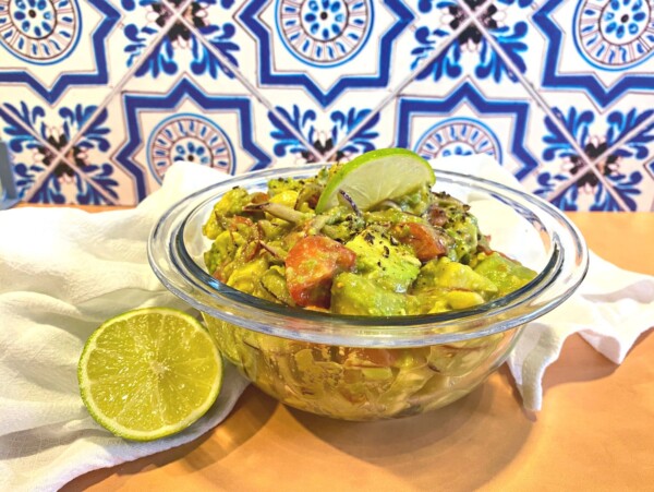 Close up of avocados, red onions and cherry tomatoes in mixing bowl. Avocado salad