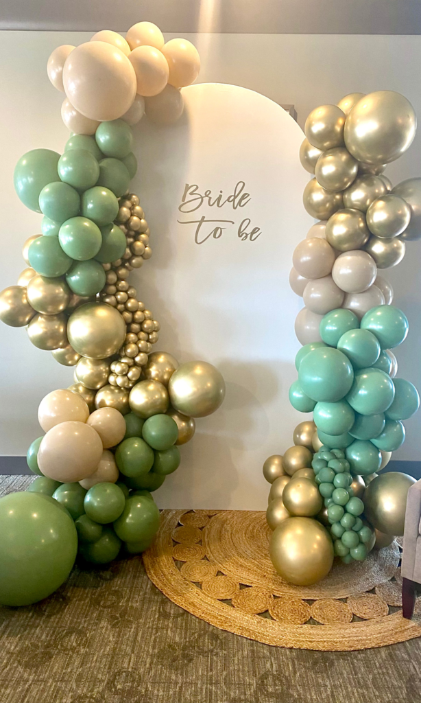 Photo of gold, green and seafoam blue balloon garland on bridal shower sign