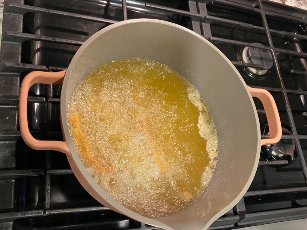 Photo of fried fish on a stove top being cooked in grease