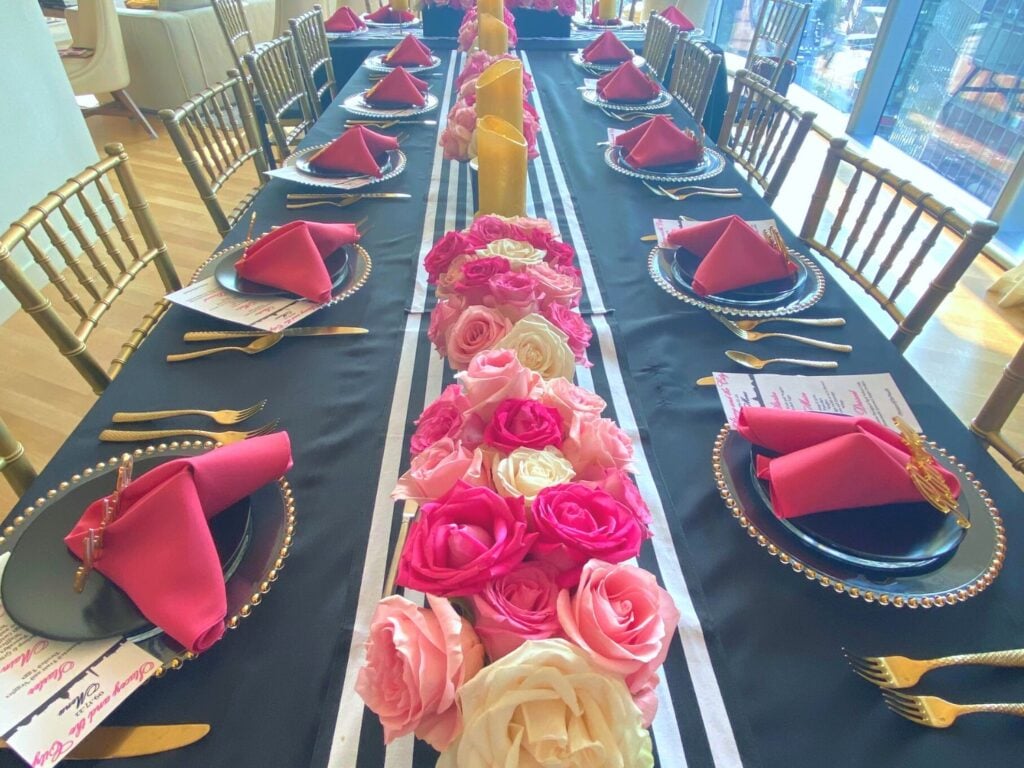 Photo of bridal shower table that's pink, black, white and gold with custom bride chair cover
