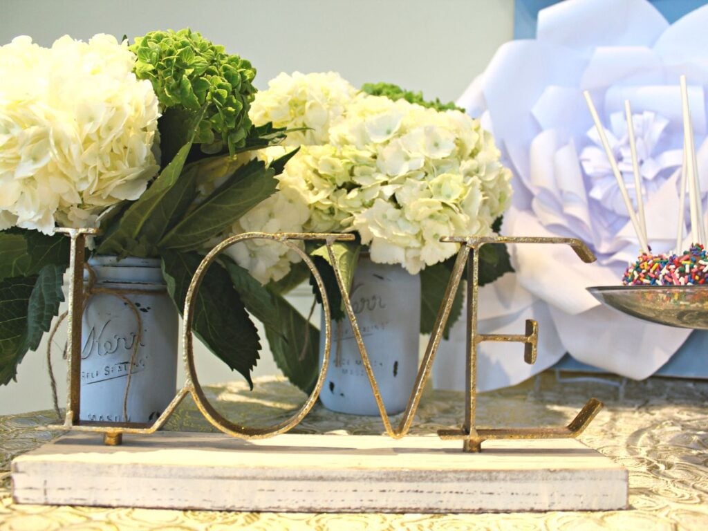 Photo of a sign that says love next to flowers