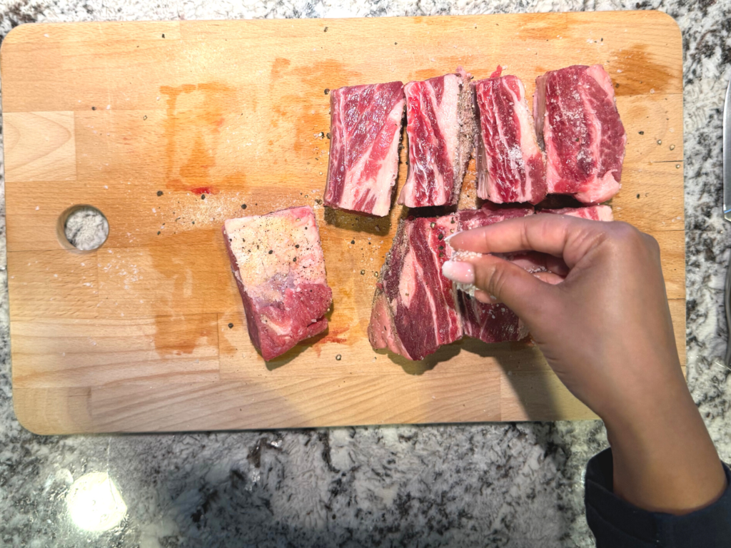 seasoning braised beef short rib on wooden cutting board
