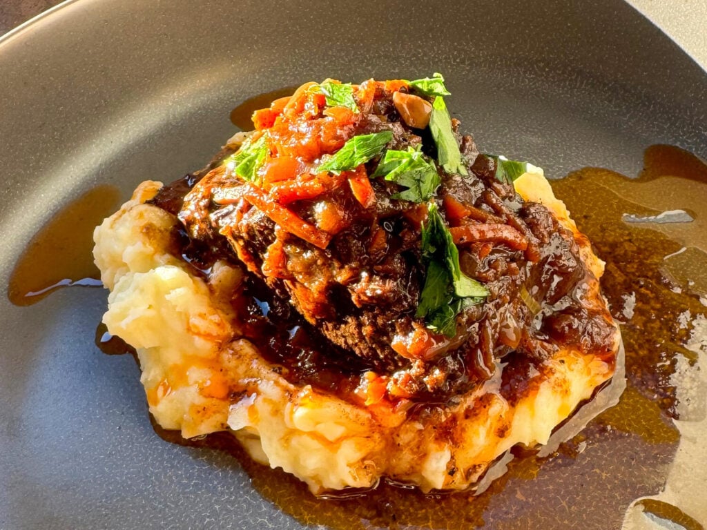 Overhead photo of braised beef short ribs on a bed of potatoes