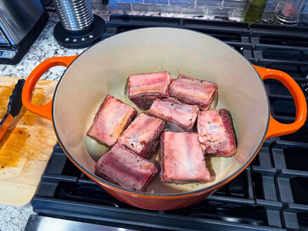 photo of short ribs in a dutch oven pan searing