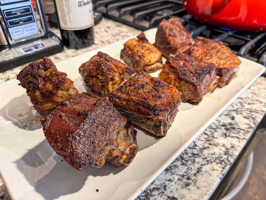 Photo of braised cooked ribs resting on a white plate