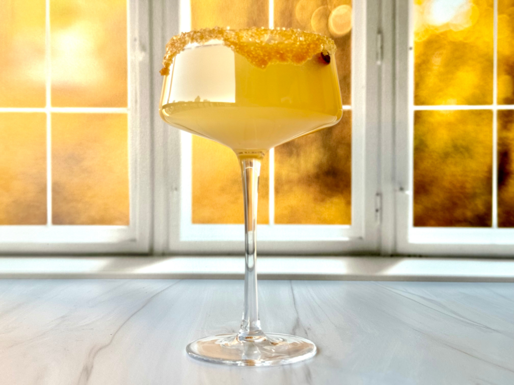 Photo of an caramel apple martini in front of an fall window