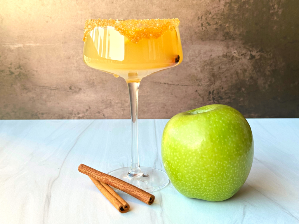 photo of a caramel apple martini next to a green apple