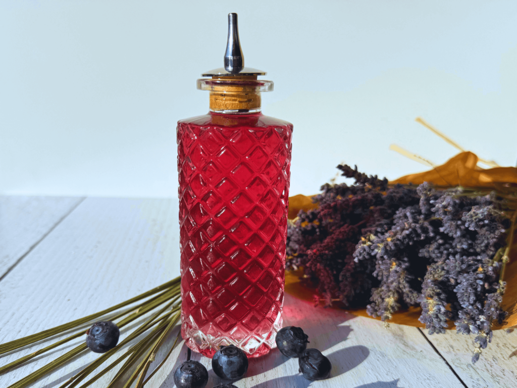 photo of lavender simple syrup in a glass bottle next to a bouquet of lavender flowers