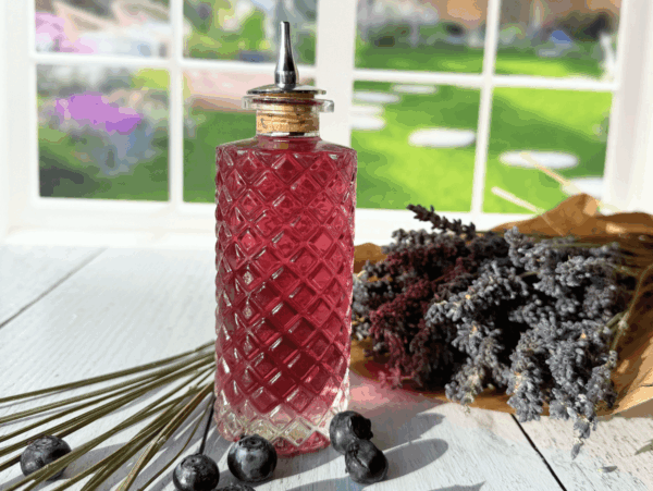 photo of lavender simple syrup in a glass bottle next to a bouquet of lavender flowers