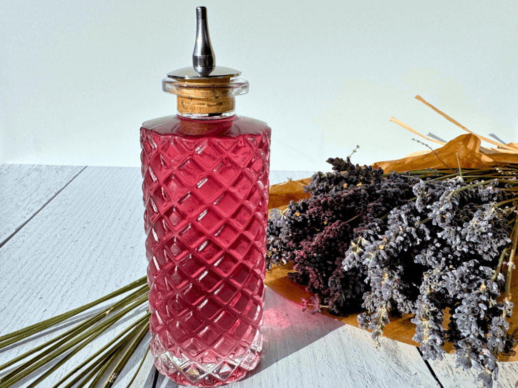 photo of lavender simple syrup in a glass bottle next to a bouquet of lavender flowers