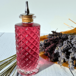 photo of lavender simple syrup in a glass bottle next to a bouquet of lavender flowers