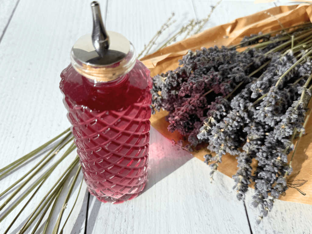 photo of lavender simple syrup in a glass bottle next to a bouquet of lavender flowers