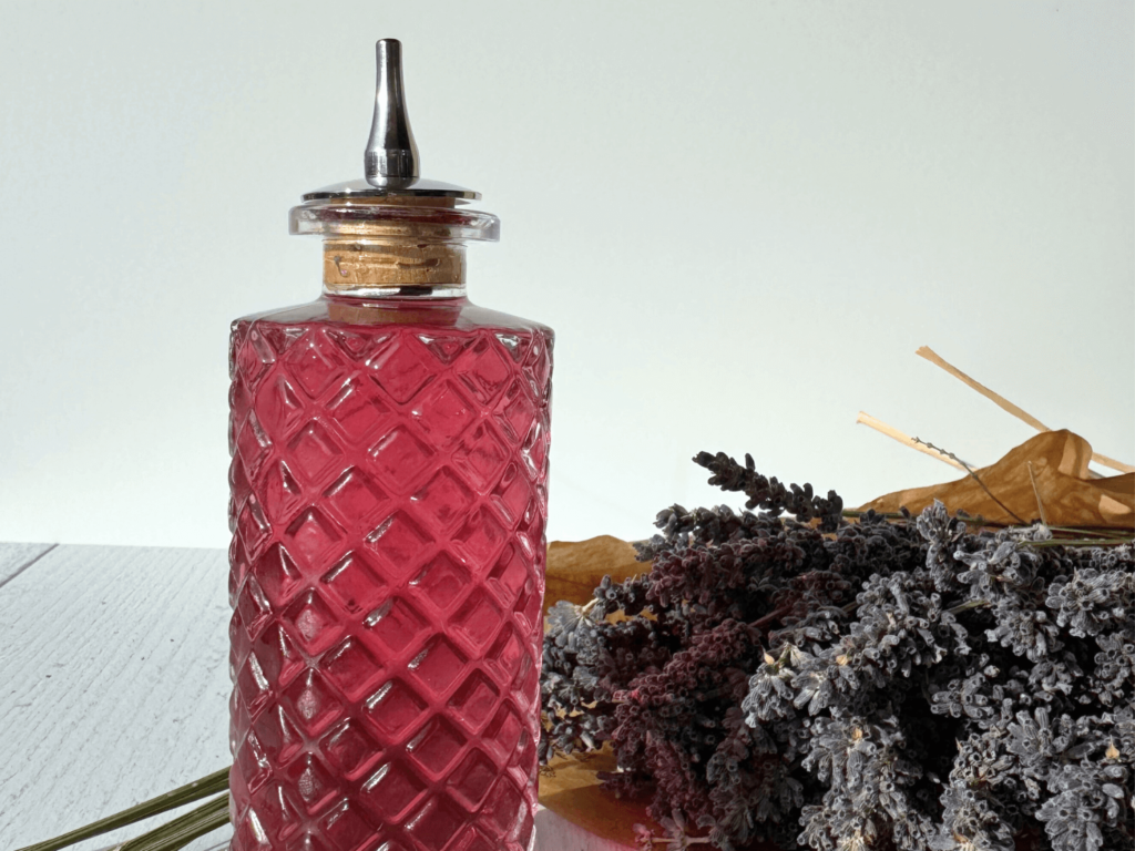 photo of lavender simple syrup in a glass bottle next to a bouquet of lavender flowers