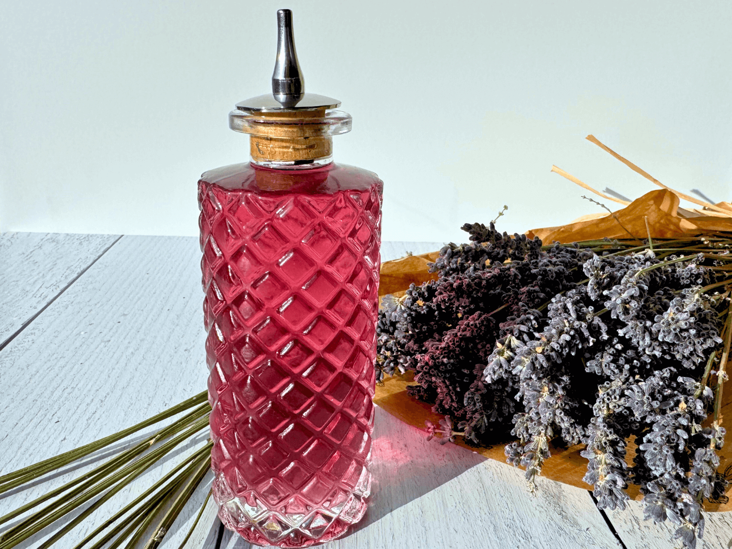 photo of lavender simple syrup in a glass bottle next to a bouquet of lavender flowers