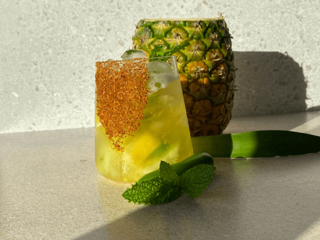 photo of a margarita with a pineapple in the background