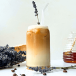 Photo of an iced lavender latte next to a honey jar and a bouquet of lavender flower buds