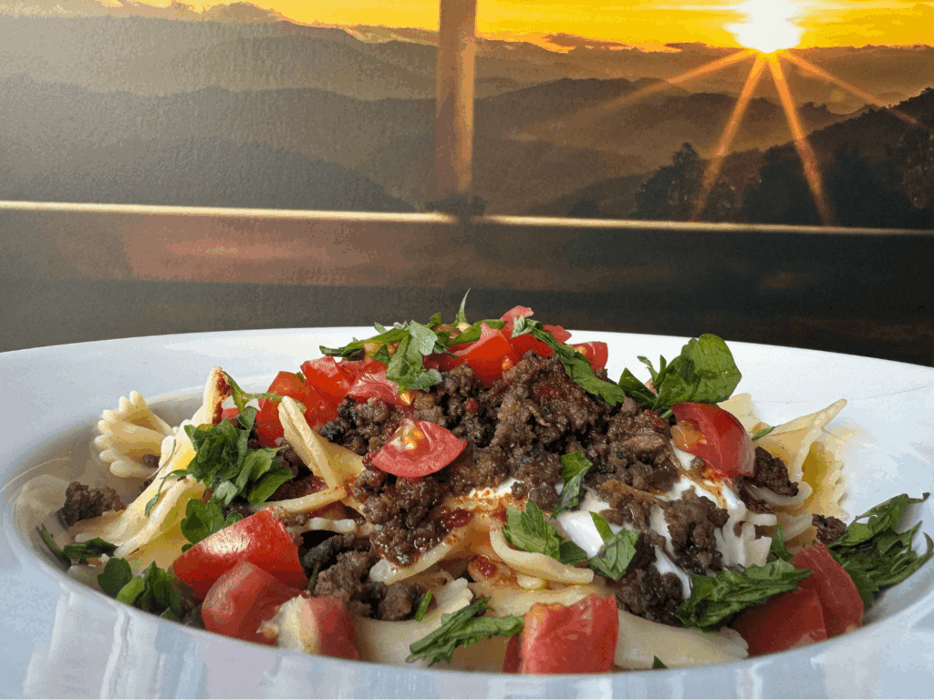 Final photo of Turkish Pasta in a white bowl in front of a sunset
