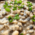 Close up photo of cooked black-eyed peas topped with chopped green onions as a garnish