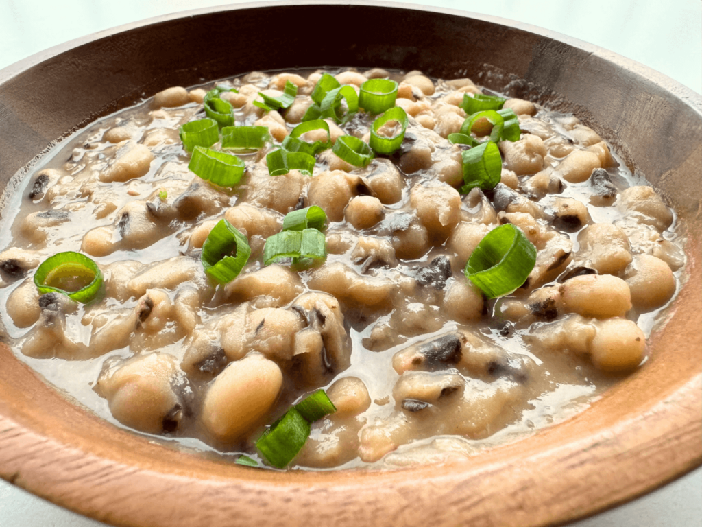 Close up photo of cooked black-eyed peas topped with chopped green onions as a garnish