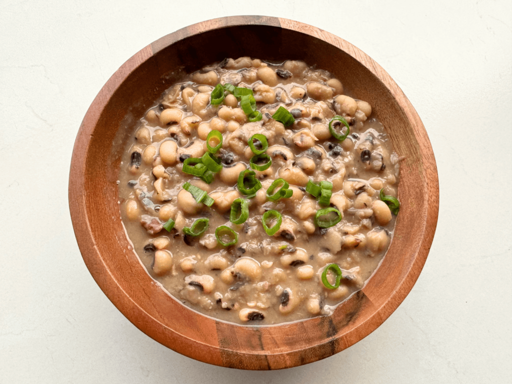 Close up photo of cooked black-eyed peas topped with chopped green onions as a garnish