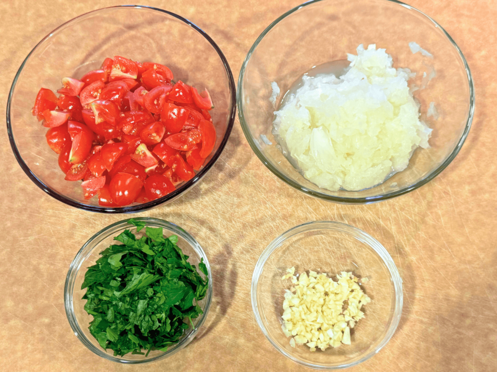 Photo of fresh ingredients such as tomatoes, onions, garlic, and parsley for Turkish pasta (Yalancı Mantı)