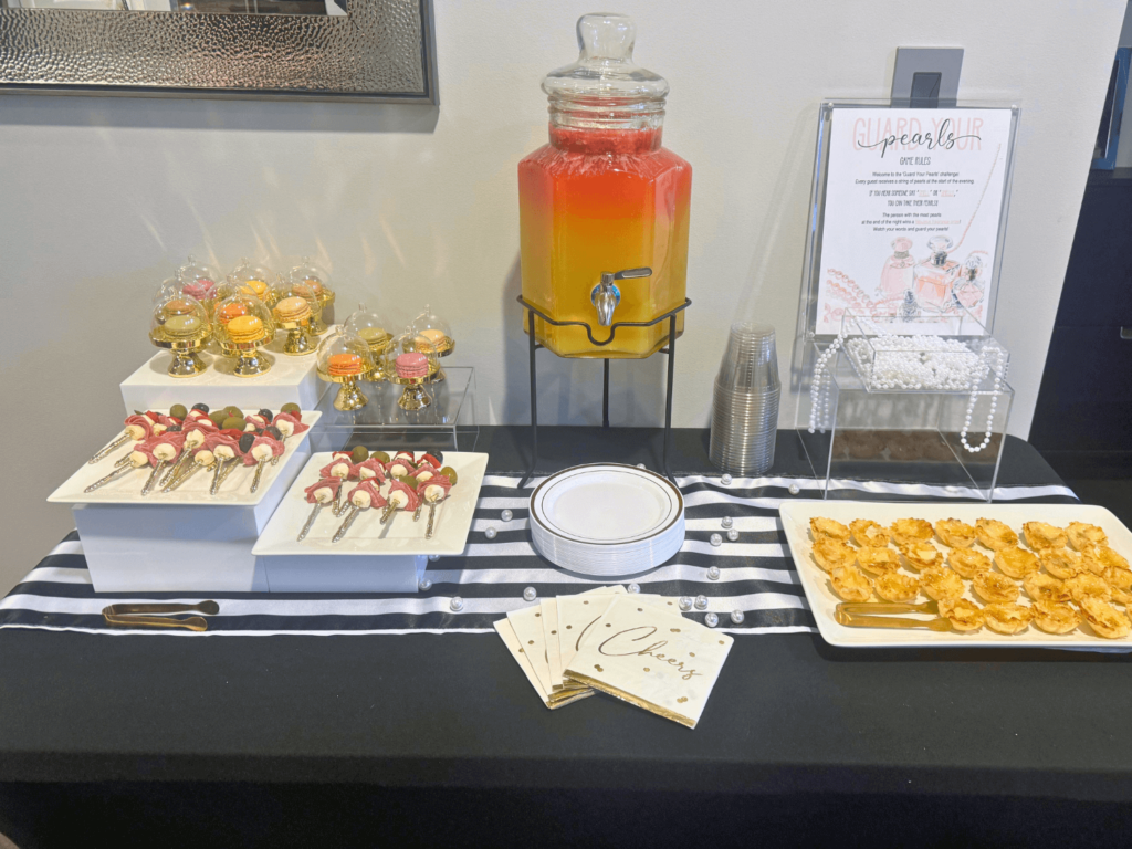 wide view of appetizer table that contains mini brie bites and antipasto skewers and punch