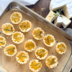 Close up photo of phyllo shells, brie cheese and peach pepper jelly on a wooden cutting board