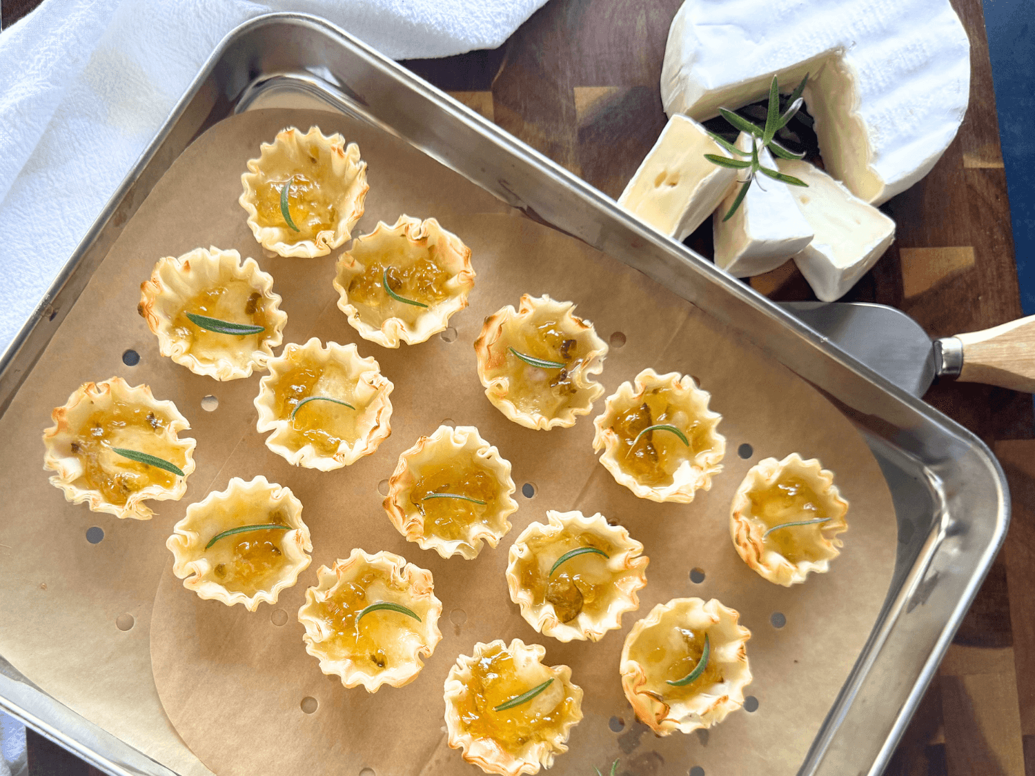 Close up photo of phyllo shells, brie cheese and peach pepper jelly on a wooden cutting board