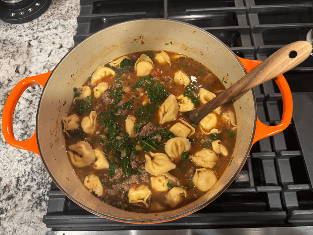 photo of cooked tortellini soup in an orange pot