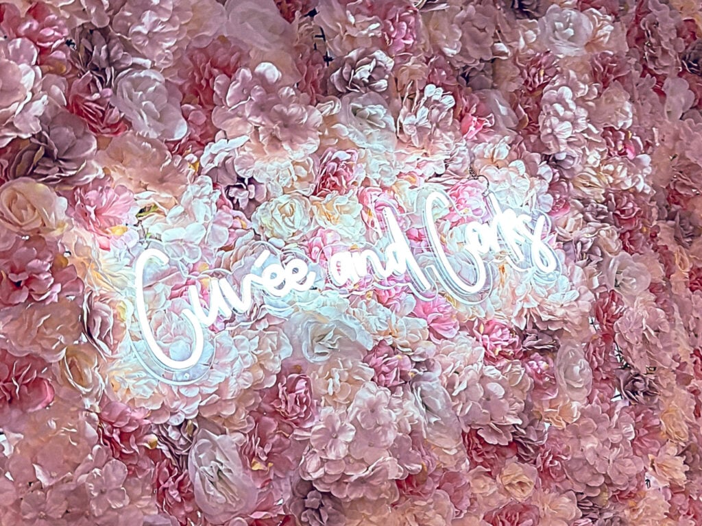 Close up photo of cuvée and corks sign on a flower wall