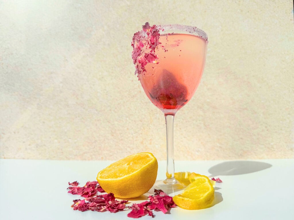 Photo of a rosé martini with lemon slices and crushed rose petals