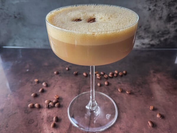 photo of an espresso martini with froth and coffee beans