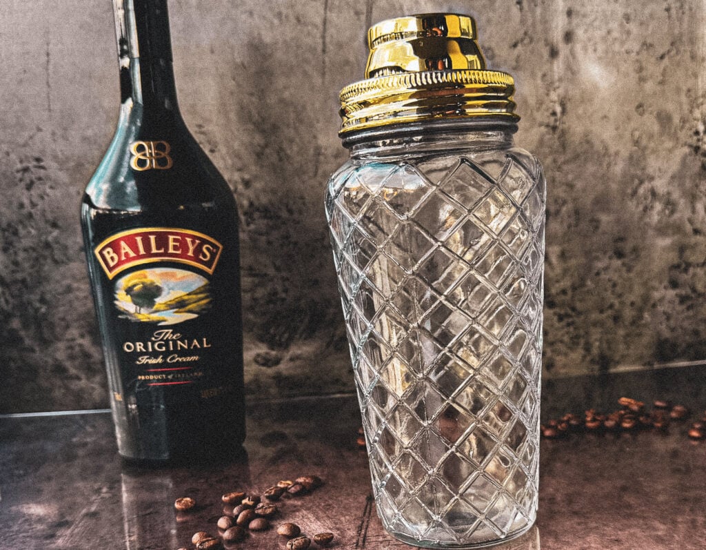 Photo of an espresso martini next to a cocktail shaker