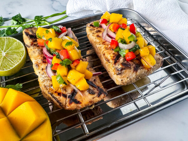 Close up photo of grilled fish with mango salsa on top